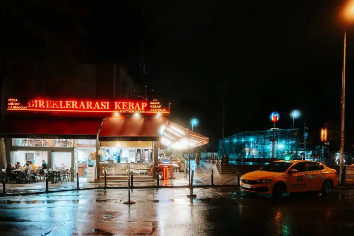 Gece ıslak sokakta bekleyen sarı taksi